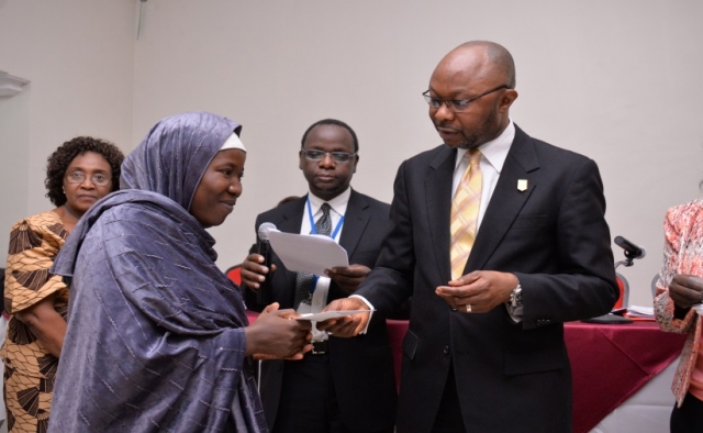 Mr Awute handing over WHO scholarship to one of the benefiting tutors