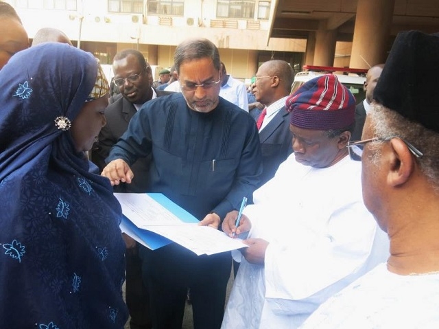 The Honourable Minister signing the hand-over documents while the WR watched