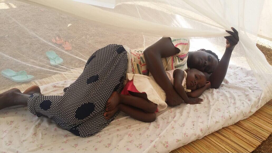 Mother and baby sleeping under a mosquito net  