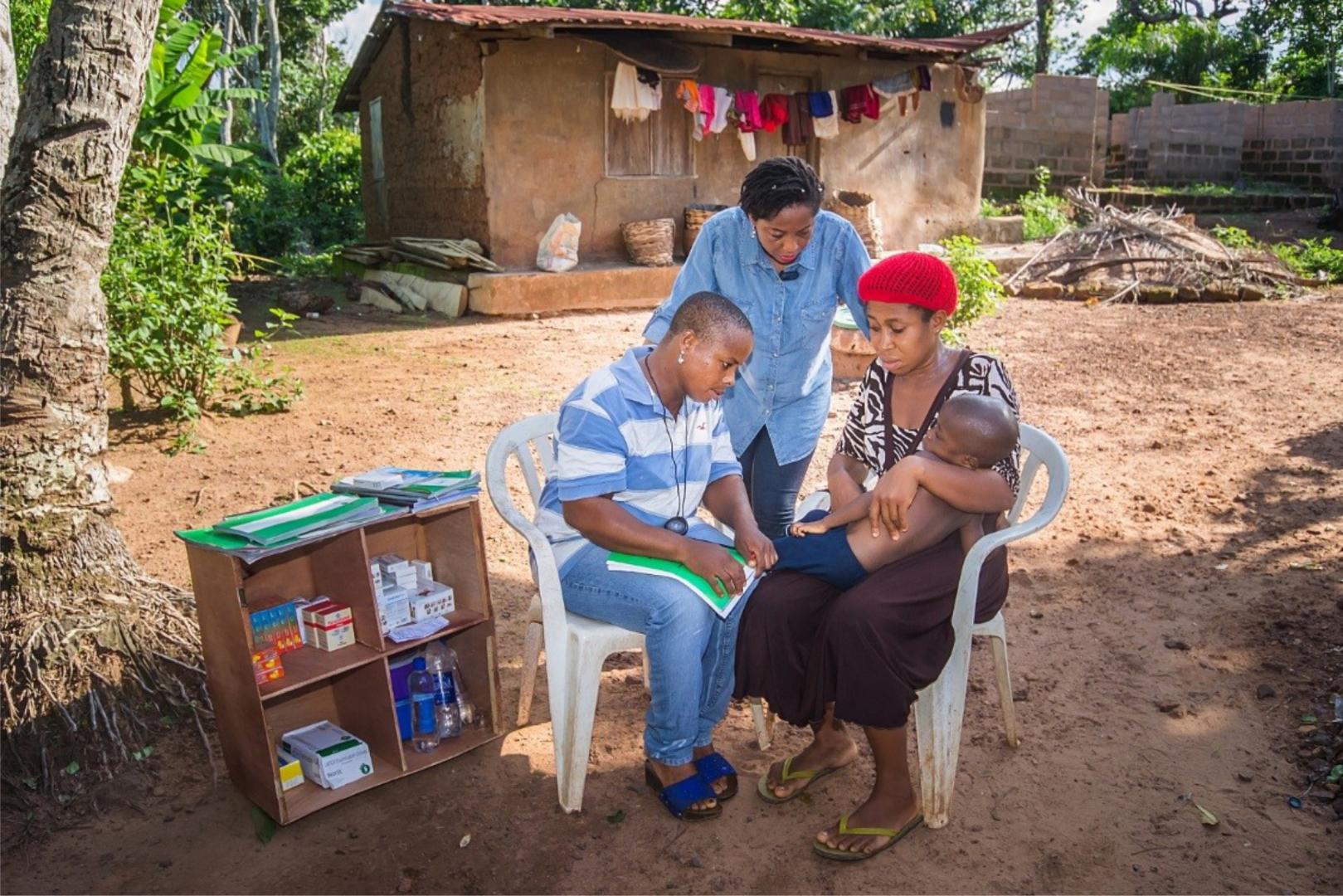 Community health worker assessing a sick child in a community