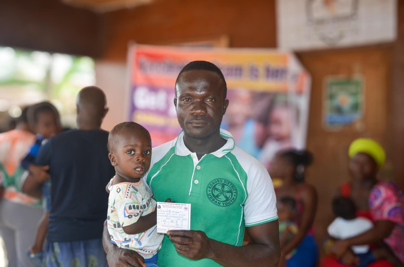 Shedrick Barlee, with his one-year-old son Blessed Barlee, at the vaccination campaign