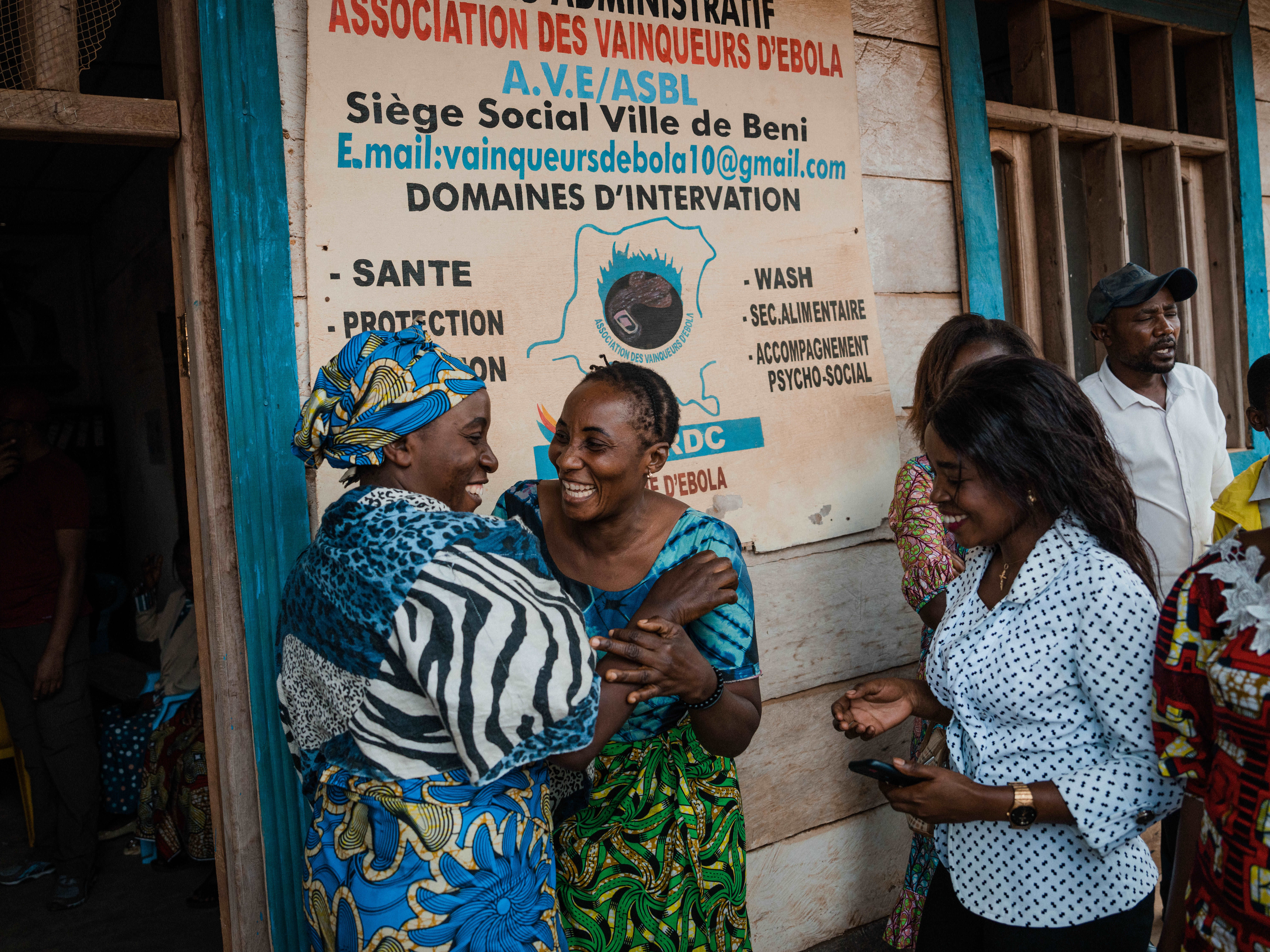 Mwamini Kavugho (à gauche) et l’une de ses collègues se donnent l’accolade devant le siège de leur Association, AVE, à Beni. Leurs rencontres ont souvent été un moment renouvelé de rire et de convivialité.  OMS/Hugh Cunningham Kinsella  