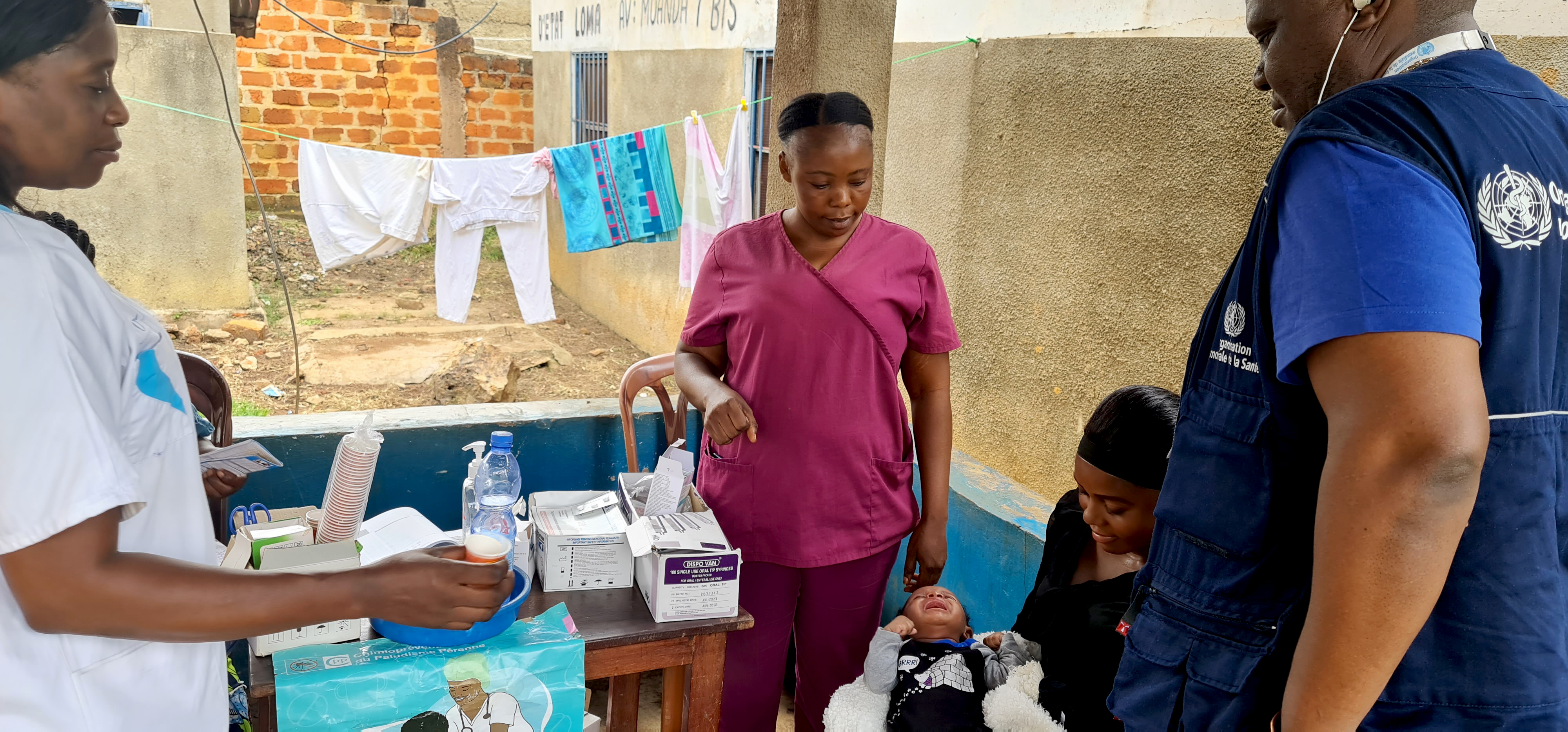 Le Dr Patrick Bahizi, point focal paludisme de l’OMS, assiste à une séance de la CPP pendant l’administration de la Sulfadoxine­pyriméthamine à un bébé, dans la zone de santé de Mbanza-Ngungu. OMS/Eugene Kabambi