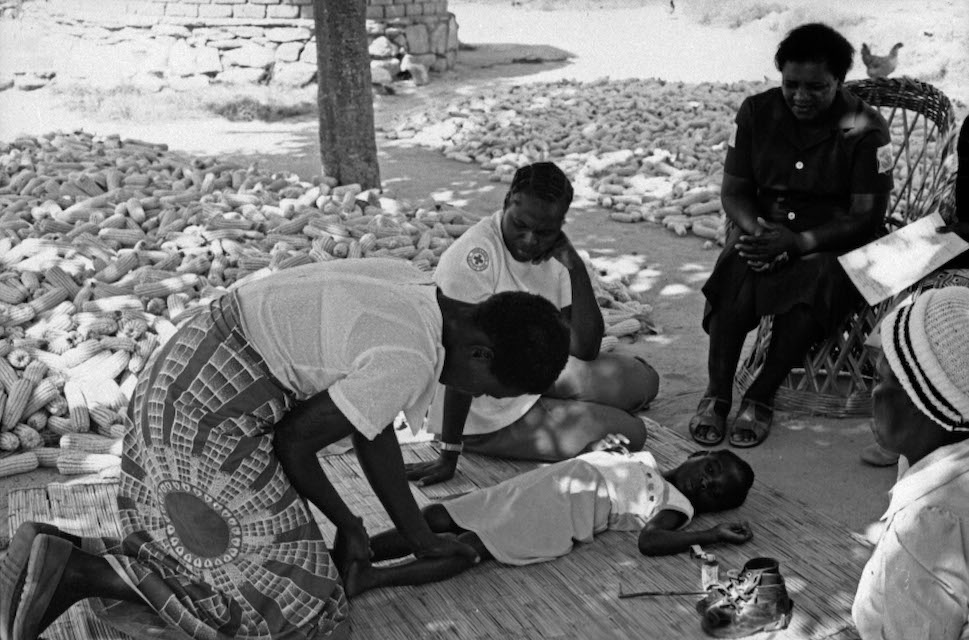 A mother gives special exercises to her child who is paralysed by polio to help prevent permanent deformation of the limbs, Kenya, 1990 © WHO