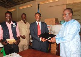 Hon. Omar Sey receiving the signed document of the handed-over items from WR