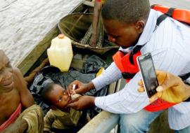 Vaccinator immunizing an eligible child in a boat with OPV during IPDS from his own boat