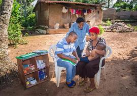 Community health worker assessing a sick child in a community