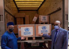 The Minister (left) and WR showing some containers of the donated ventilators to journalists present at the hand-over ceremony.jpg 