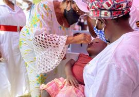 Ms Teopista's son receives his Oral Polio Vaccine drops from the Minister of State in Charge of General Duties Hon. Hanifah Kawooya at the vaccination campaign launch