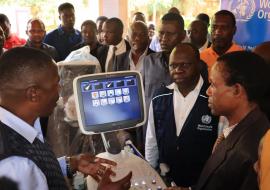 The Kigoma Regional Commissioner receiving a briefing from the regional radiographer, witnessed by the WHO Country Representative, Dr. Yoti and other regional and district authorities.