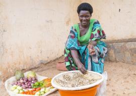 Marie Jeanne sits outside selling fruits and vegetables