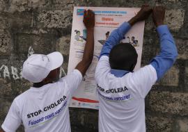 Health workers put up a poster on preventing cholera during an outbreak in Kinshasa in 2016. 