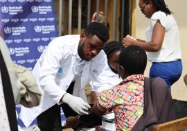 A MEDSAR student checking a woman's blood pressure at the Nyabahinga Market