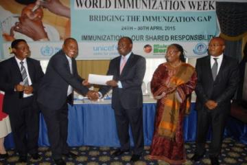 Cabinet Secretary Mr James Macharia awards a certificate to Dr Ephantus Maree, Head of Unit of Vaccine and Immunization Services (UVIS) at the launch of World Immunization week in Kenya, Nairobi. Looking on: Dr Jackson Kioko, Head, DPPHS, Dr Custodia Mandlhate, WHO Country Representative and Dr Nicholas Muraguri, Director of Medical Services