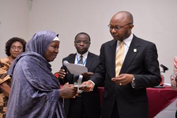 Mr Awute handing over WHO scholarship to one of the benefiting tutors