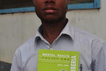 A mental health worker displaying a copy of the Mental Health Policy and Strategic Plan