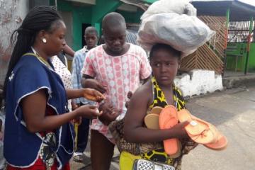 A vaccinator administring polio drops to a child on its mothers back