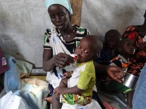 Woman giving PlumpyNut nutritional aid to her child in South Sudan, former Unity State