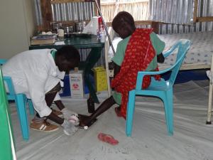 Health care worker dressing wound on a woman’s leg in Bentiu