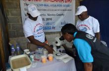 A WHO staff viewing a mosquito under a microscope at the exhibition