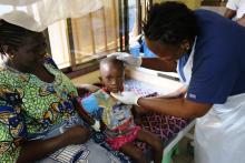 Photo of a nurse attending to Moses while Ebie looks on. The child's health has improved considerably due to the quality of care he received at the hospital