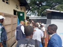 Le Dr Michel Yao discutant avec son collègue de l’UNICEF lors de la visite de la salle abritant le laboratoire mobile de l’hôpital général de référence de Tchomia. OMS/Eugene Kabambi