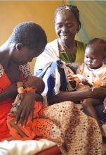 With Bakhita on her lap, Tereza encourages Ajonga to breastfeed her granddaughter, baby Akot.