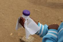 Learner holding stool sample container 