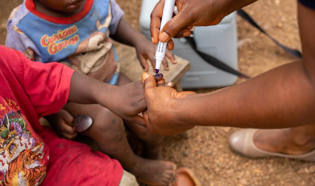 A health worker marking the finger of a child after vaccinating him